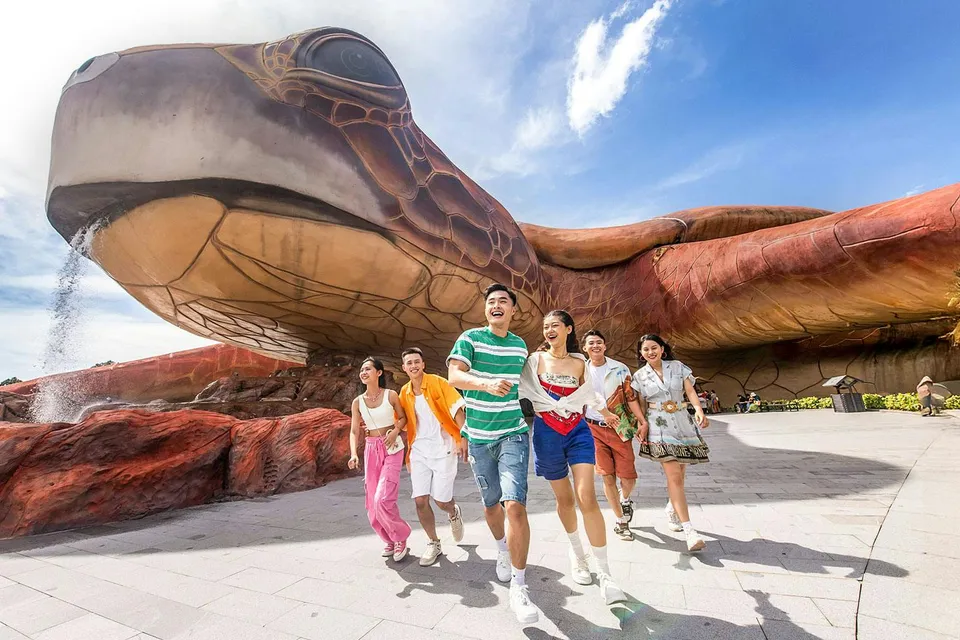 Guests enjoying VinWonders Phu Quoc near giant turtle sculpture.