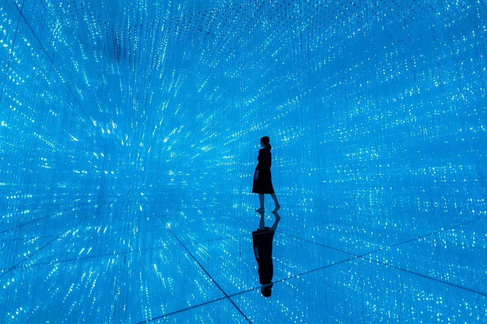 Person walking through digital light installation at TeamLab Planets Tokyo exhibit.