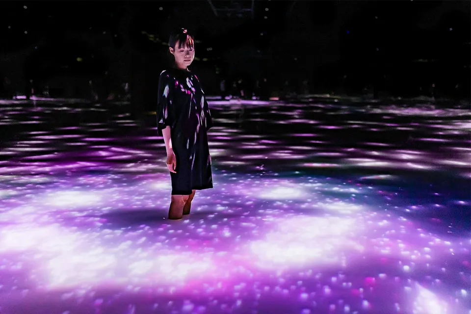 Person standing in illuminated water at teamLab Planets Tokyo exhibit.