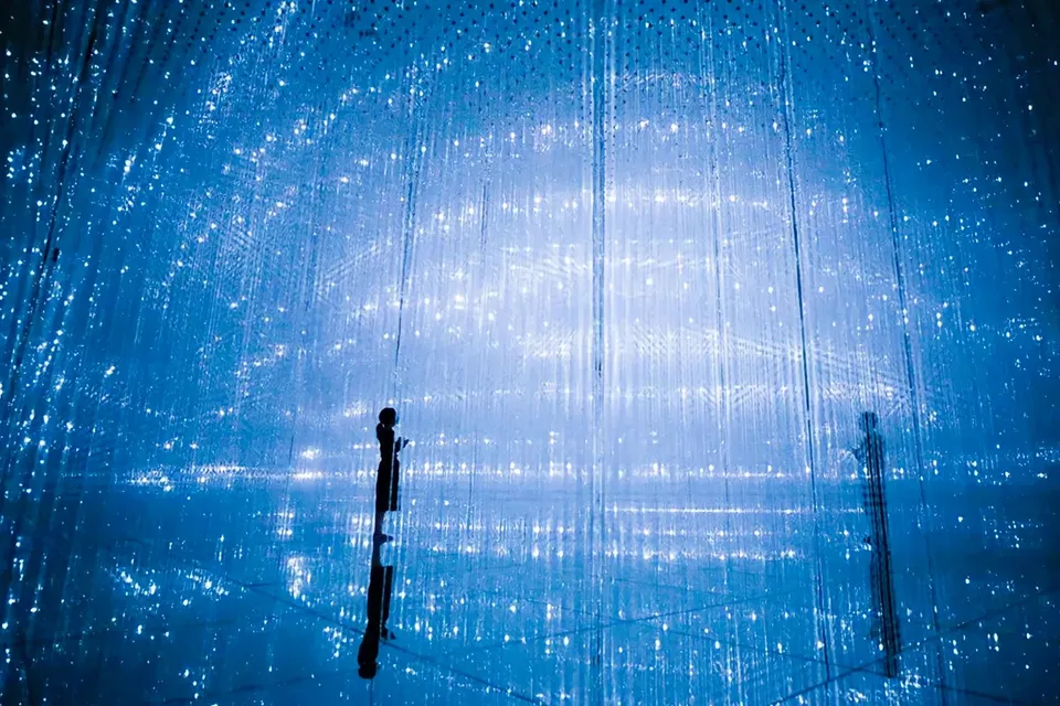 Visitors at TeamLab Planets Tokyo in a digital art installation with blue lights.