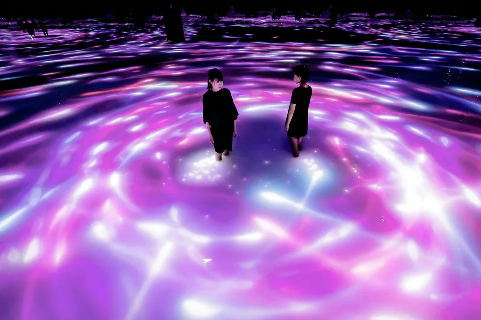 Visitors standing in illuminated water at teamLab Planets Tokyo exhibit.
