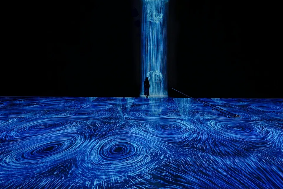 teamLab Planets Tokyo, blue light vortices installation with person standing in the flow.