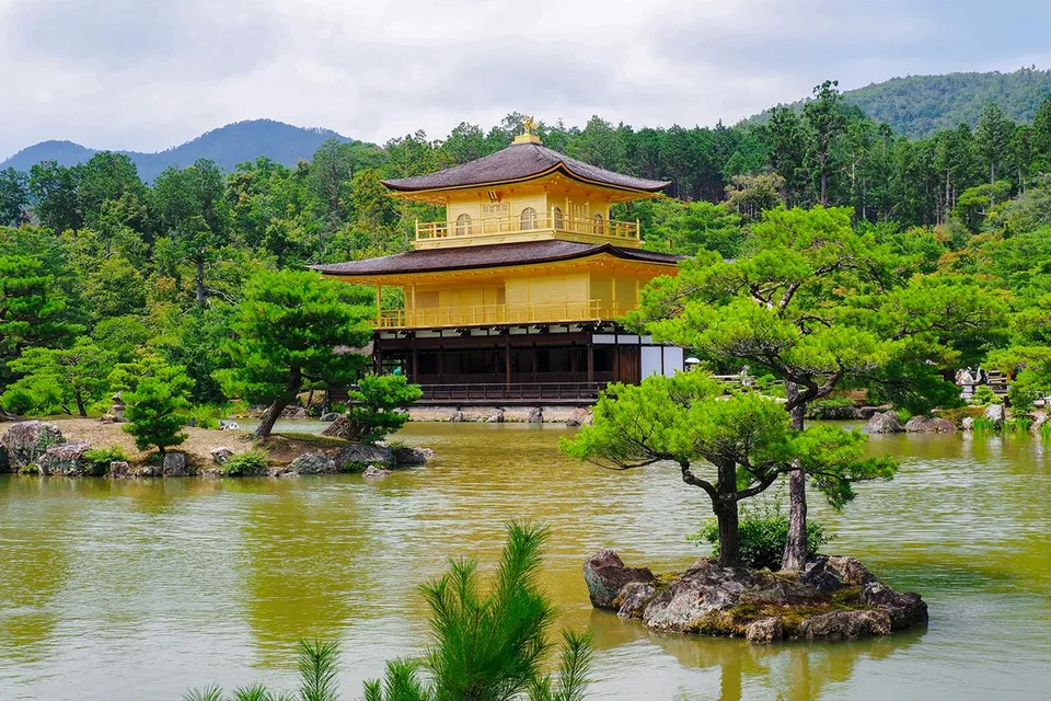 Kinkaku-ji temple in Kyoto surrounded by lush greenery and a reflective pond.