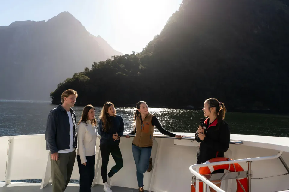 Group enjoying Milford Sound Extended Cruise with guide against mountain backdrop.
