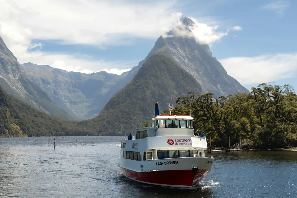 Cruise boat on Milford Sound with Mitre Peak in the background, New Zealand.