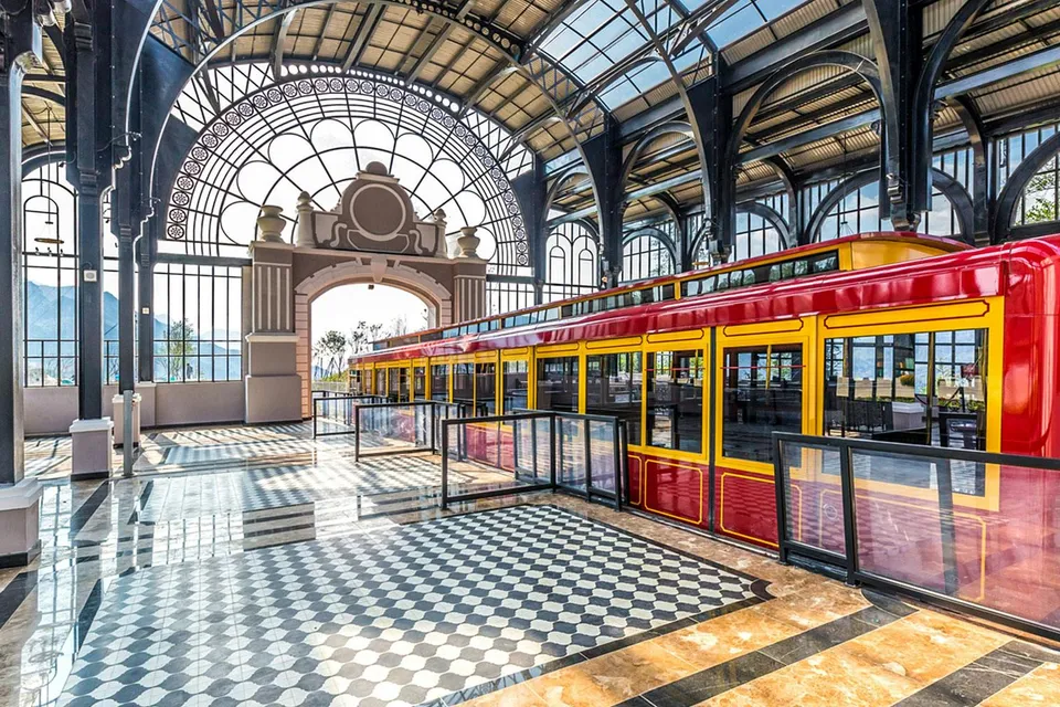 Red and yellow train inside Sun World Fansipan Legend station with arched glass roof.
