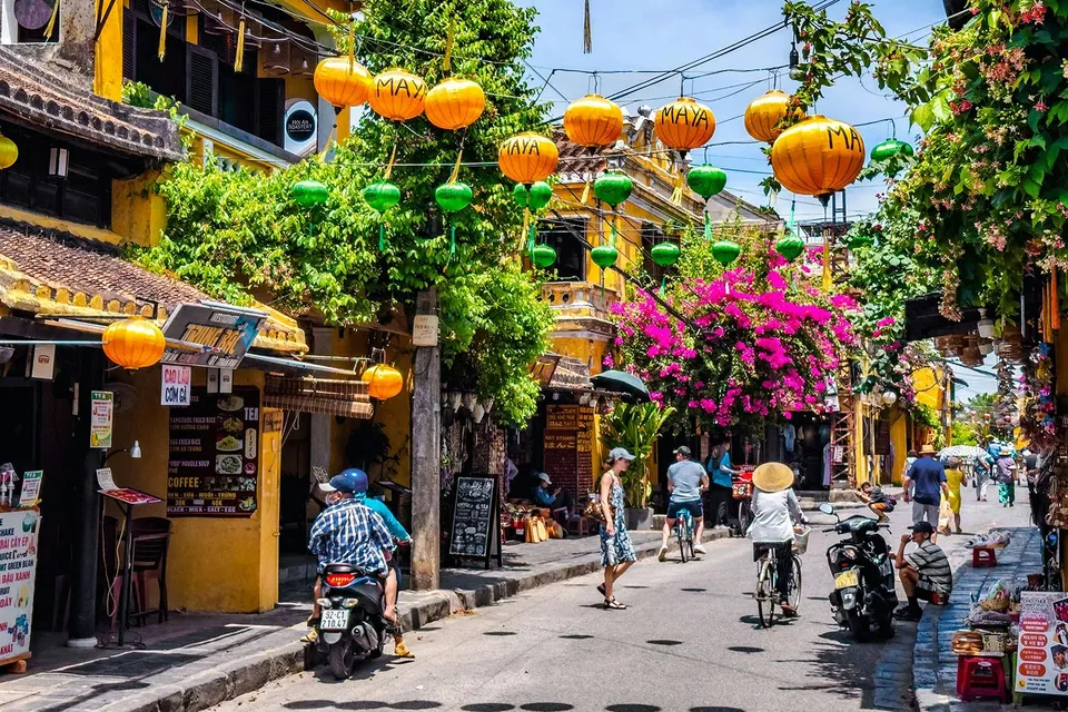 Street view in Hoi An ancient town, Vietnam, with colorful lanterns and vibrant flowers.