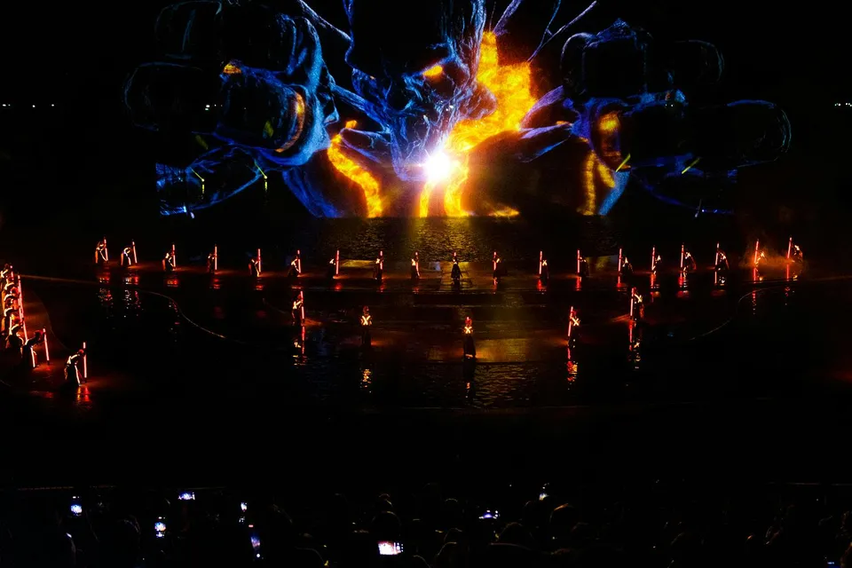 Performers with illuminated props at Kiss of the Sea Show, vibrant light display in background.
