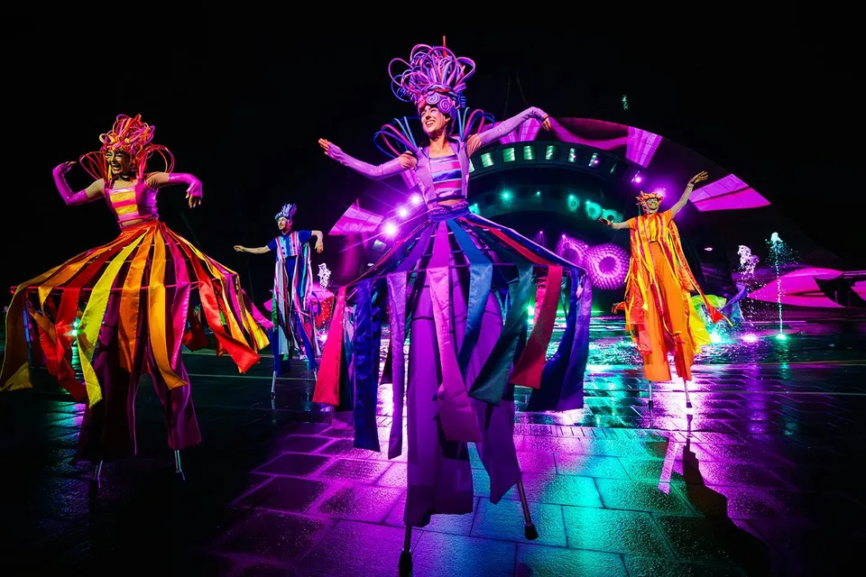 Performers in colorful costumes on stilts at the Kiss of the Sea Show.