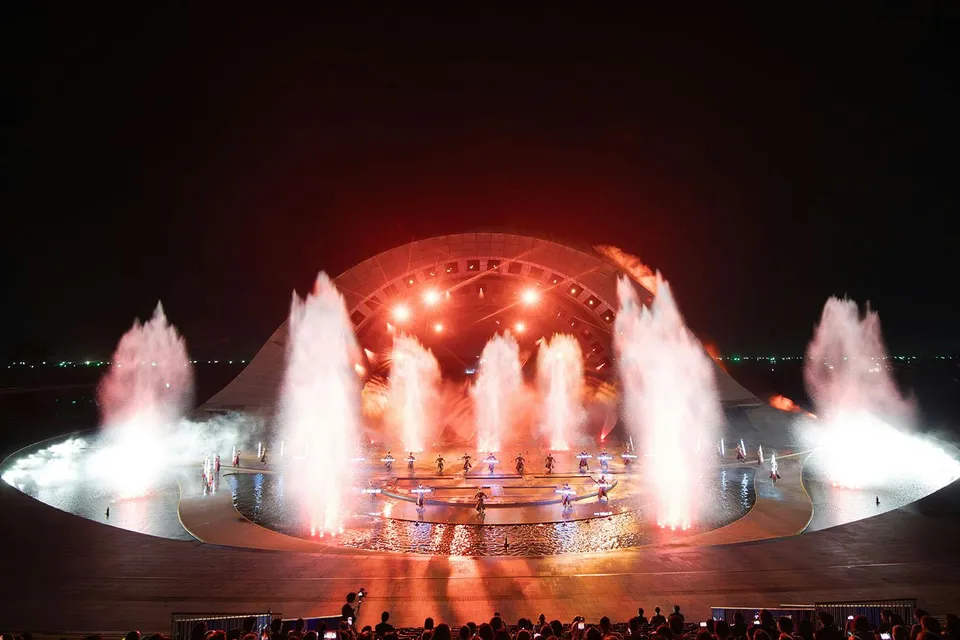 Fountain and light display at Kiss of the Sea Show, featuring performers on stage.