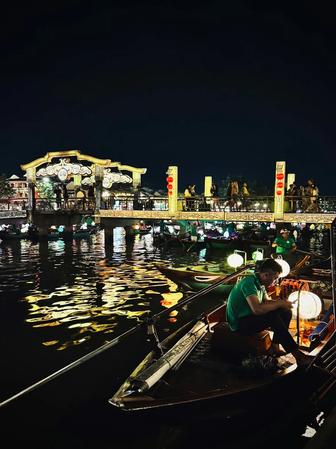 Boats on a river at night with a lit bridge