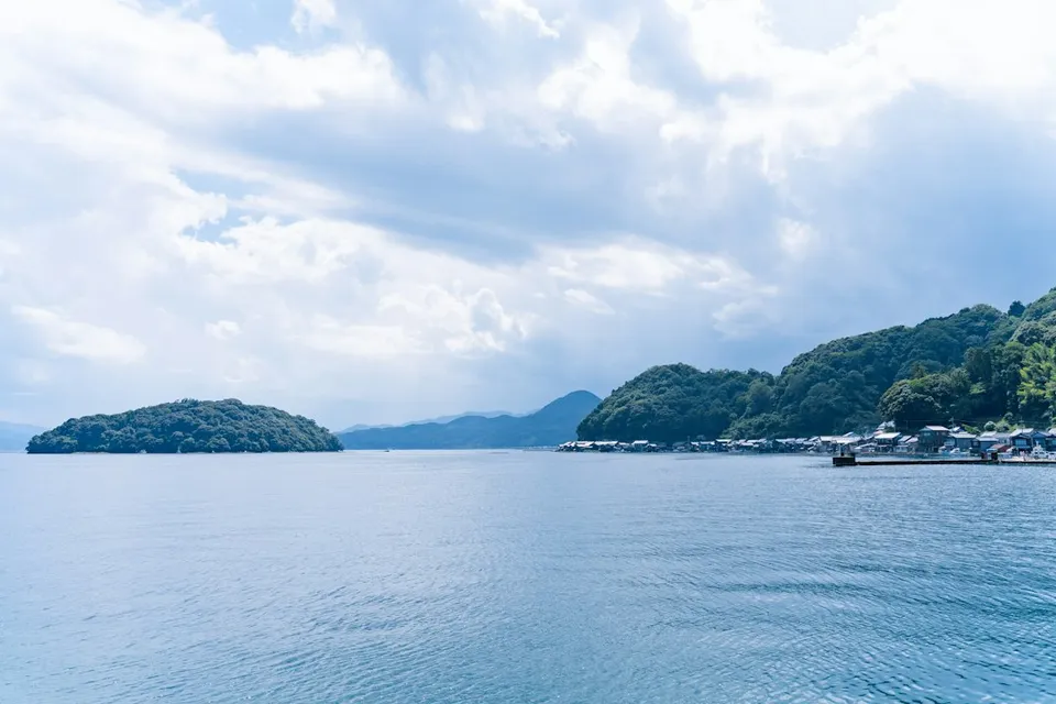 A calm bay with green islands under a cloudy sky
