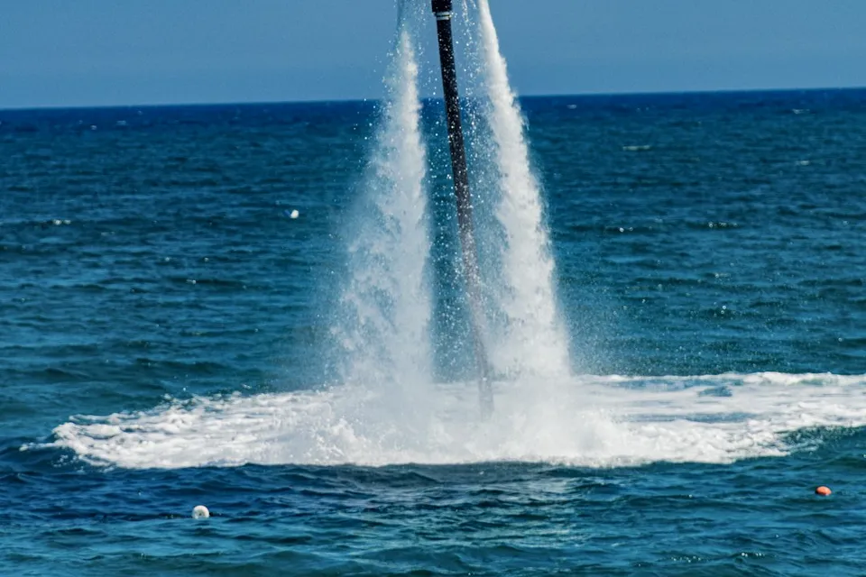 woman in black tank top and blue denim jeans standing on white surfboard on sea waves