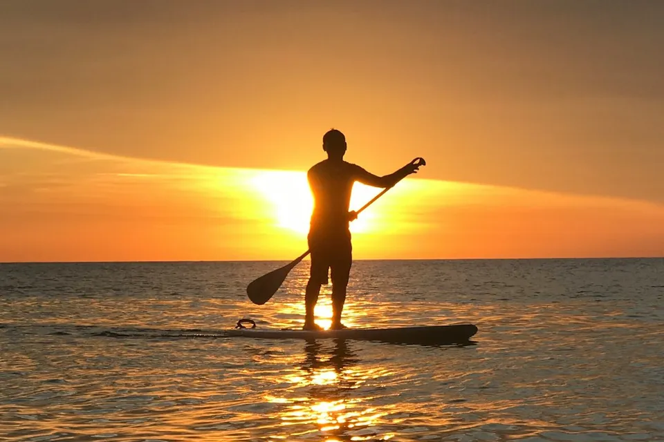 person on paddle boat during sunset