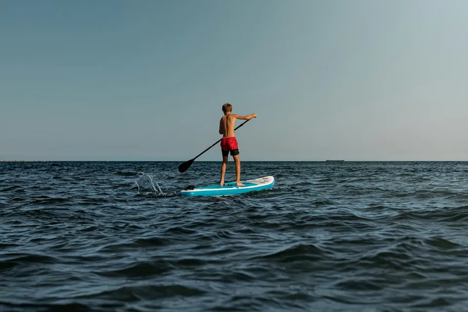 woman in blue and white surfing board on sea during daytime