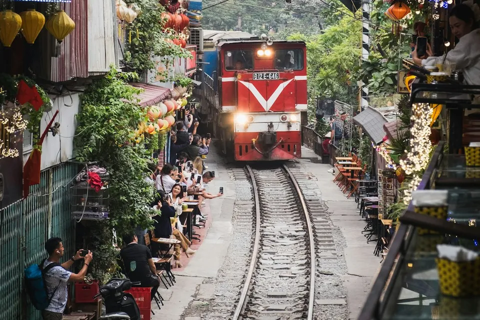 A red train traveling down train tracks next to a crowd of people