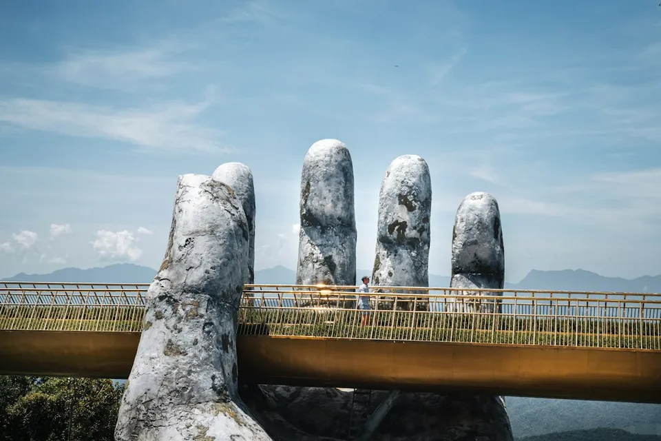 A person walking on the Golden Bridge held by a giant stone hand in Vietnam