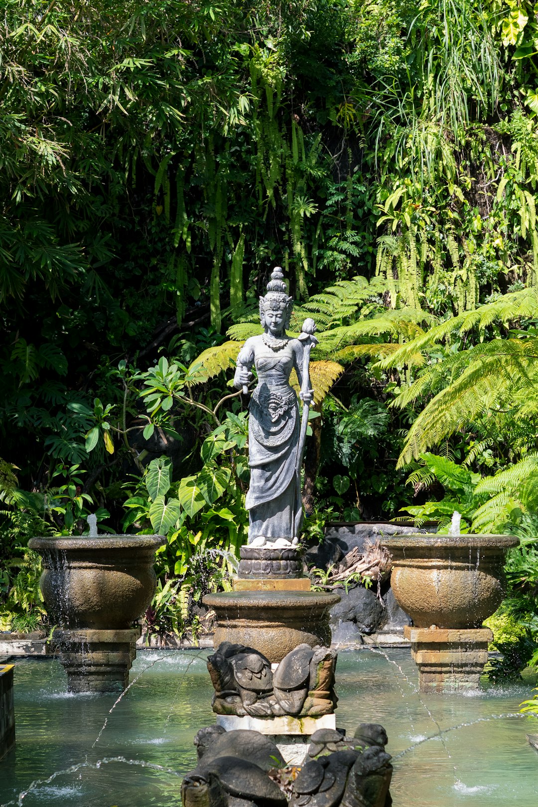 Stone statue in lush garden with fountains