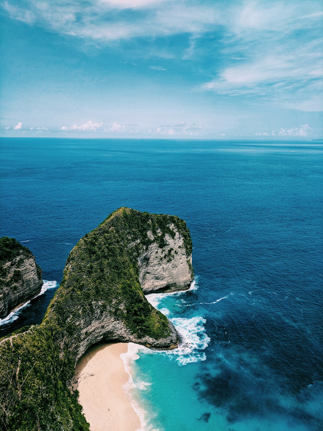 green and brown rock formation beside blue sea under blue sky during daytime