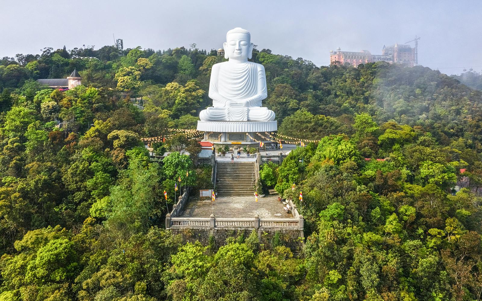 Buddha statue on Ba Na Hills, Vietnam, surrounded by lush greenery and mist.