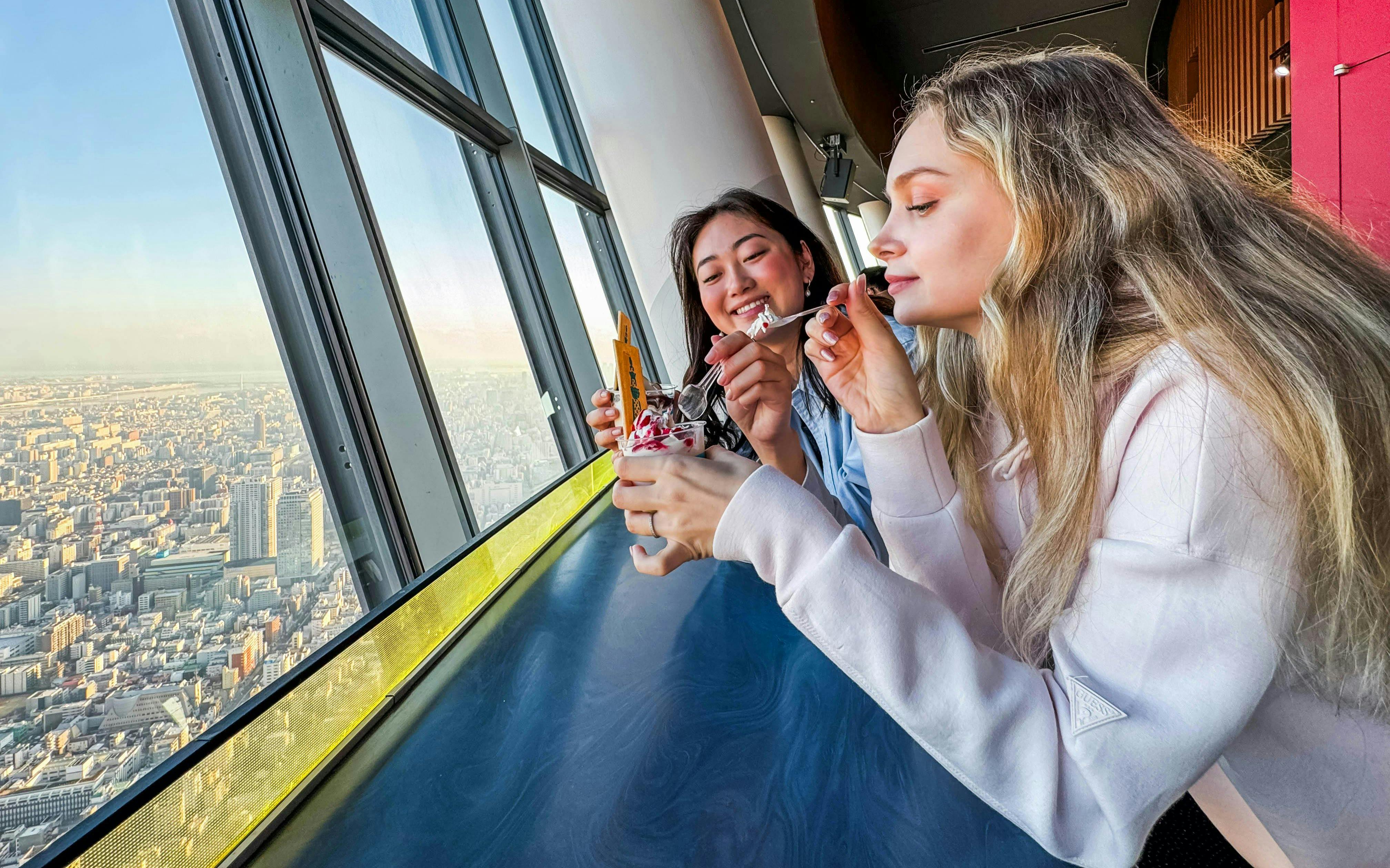 Visitors enjoying dessert with a view from Tokyo Skytree observation deck.