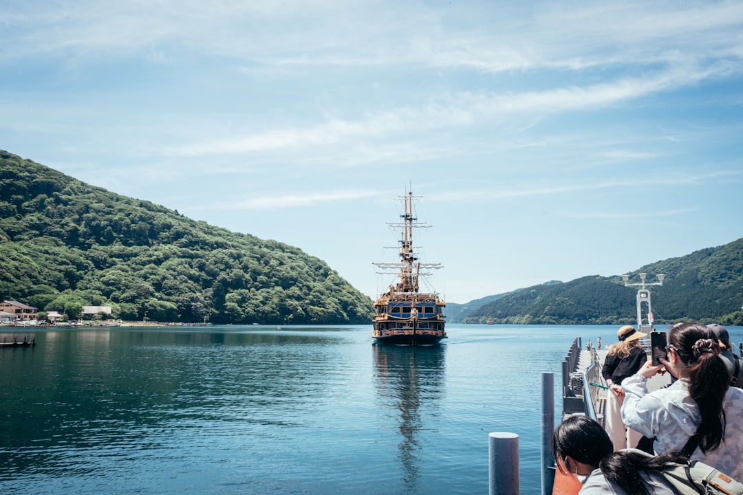 A large ship navigates a serene lake between green mountains.