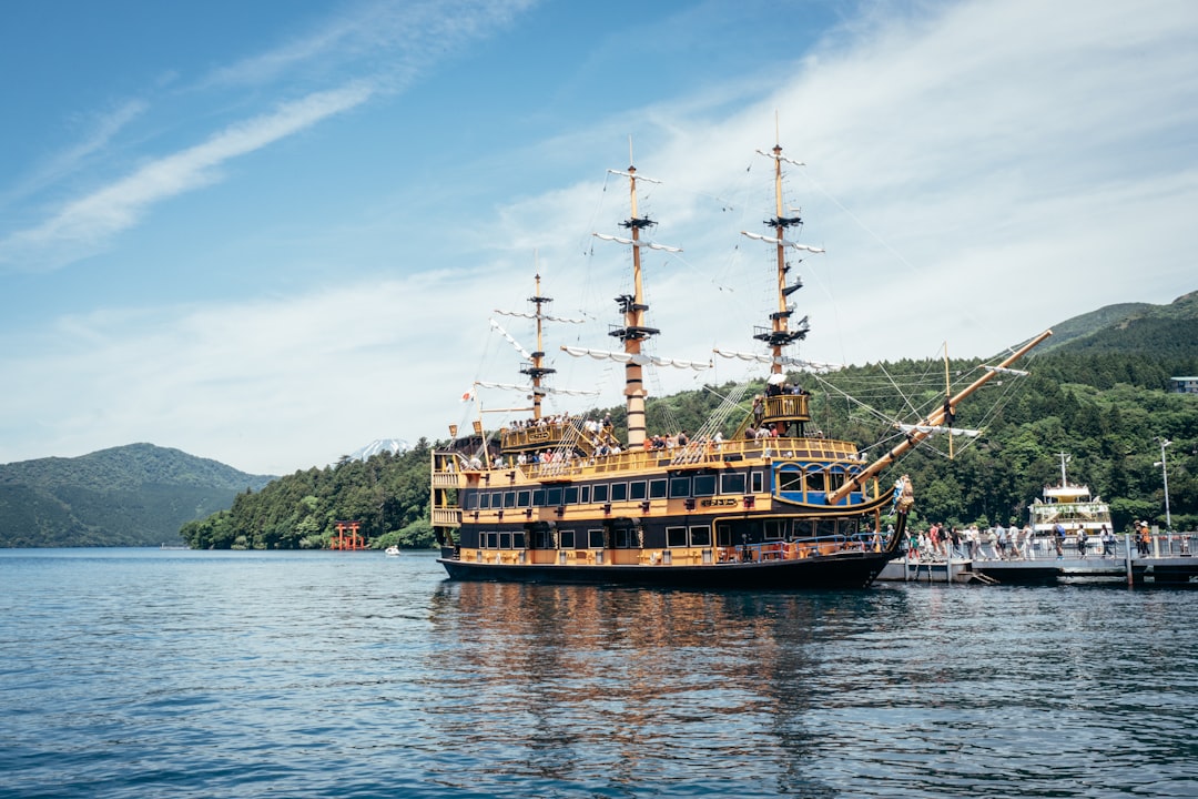 A large sightseeing ship docked on a lake with mountains.