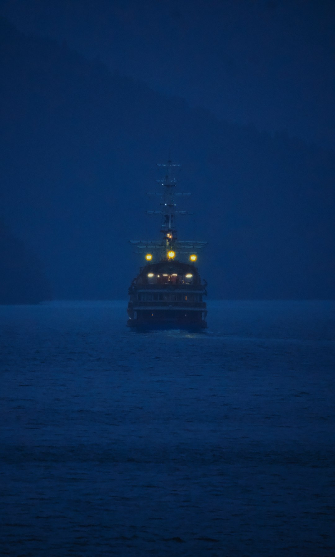 A ship sails on the ocean at night.