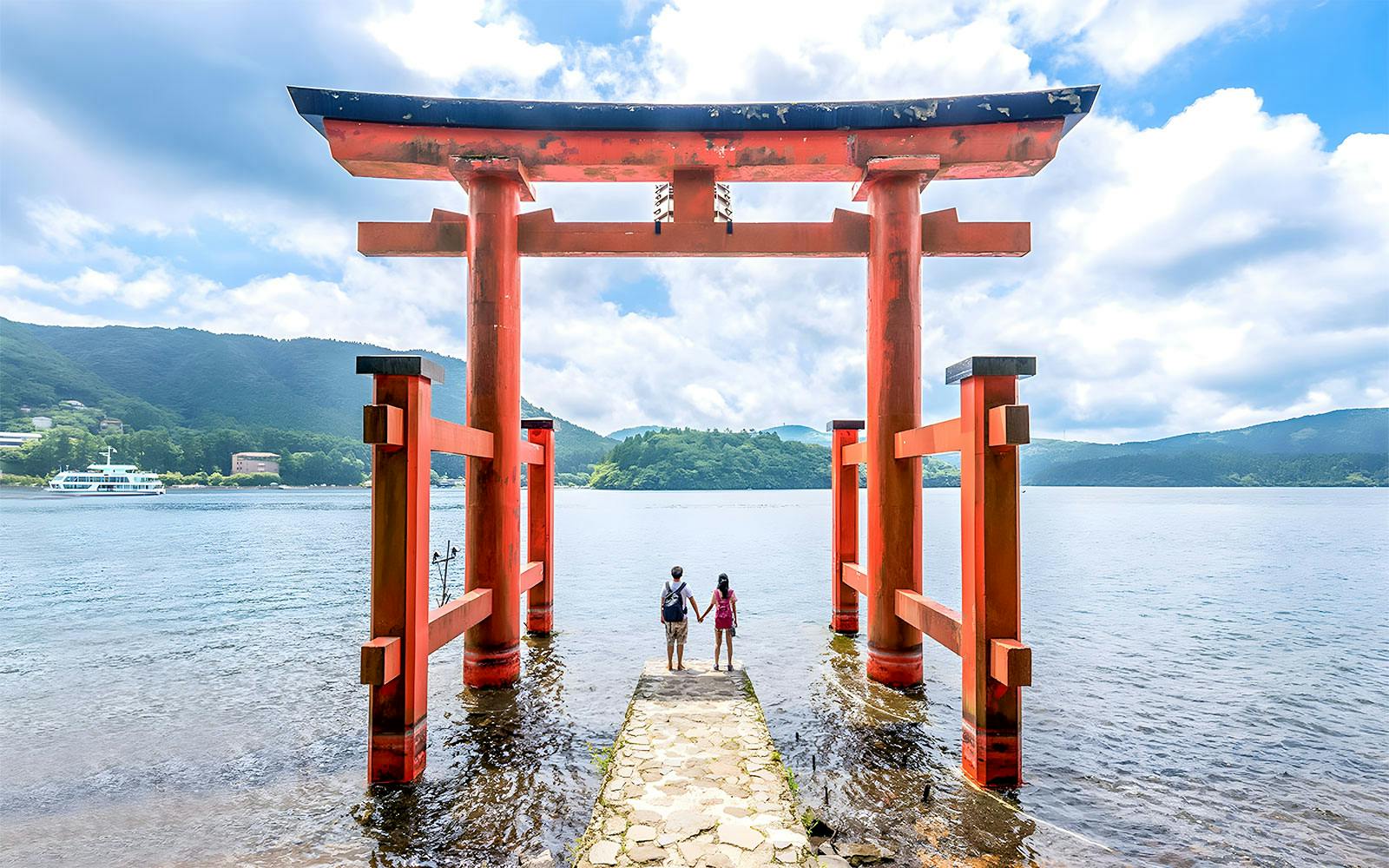 Couple standing at Hakone Torii Gate overlooking Lake Ashi, Japan.