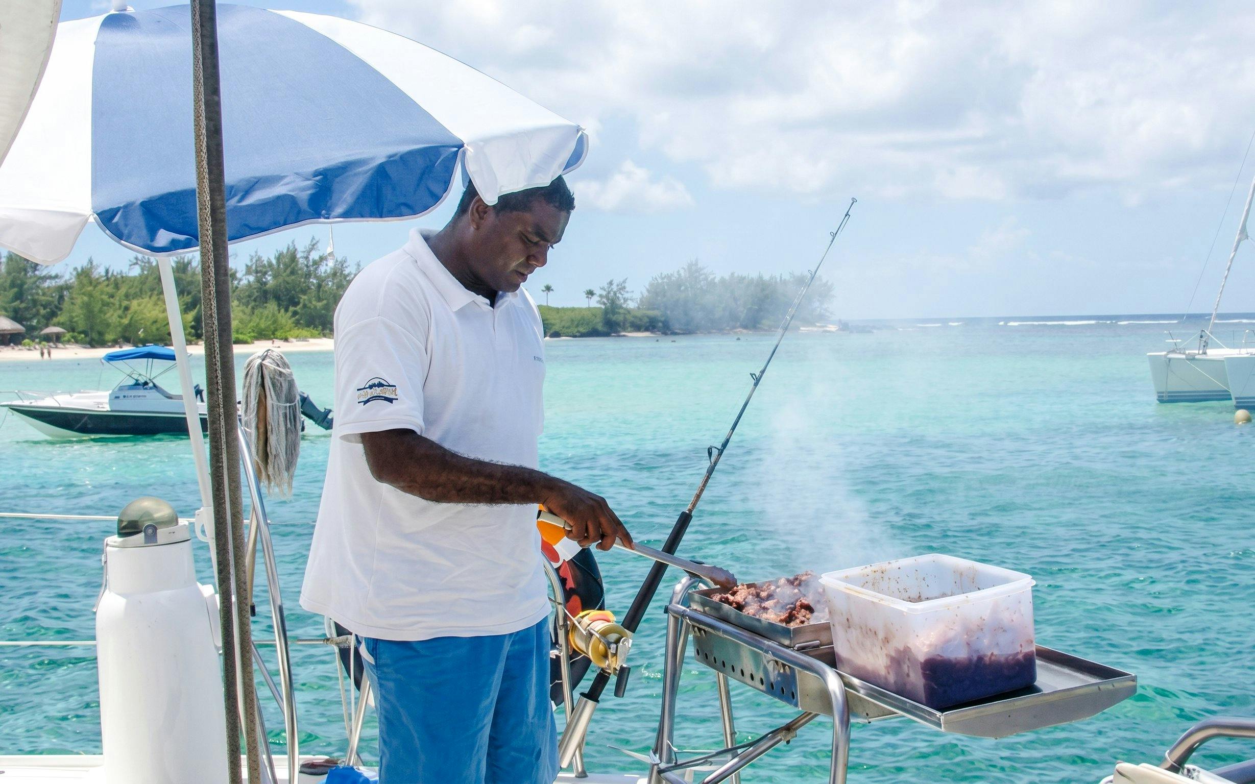 Grilling on a catamaran near Ile aux Cerfs, Mauritius, with turquoise waters in the background.