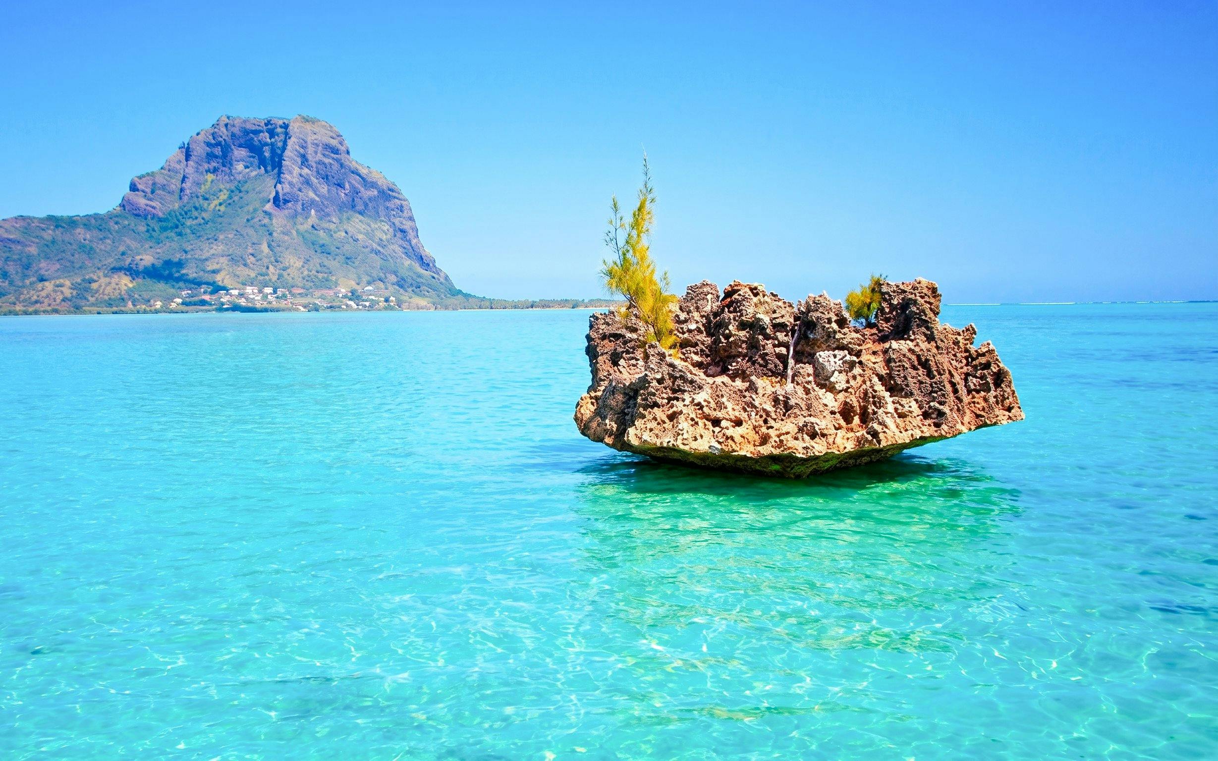 Crystal rock formation in turquoise waters with Le Morne Brabant in the background, Mauritius.
