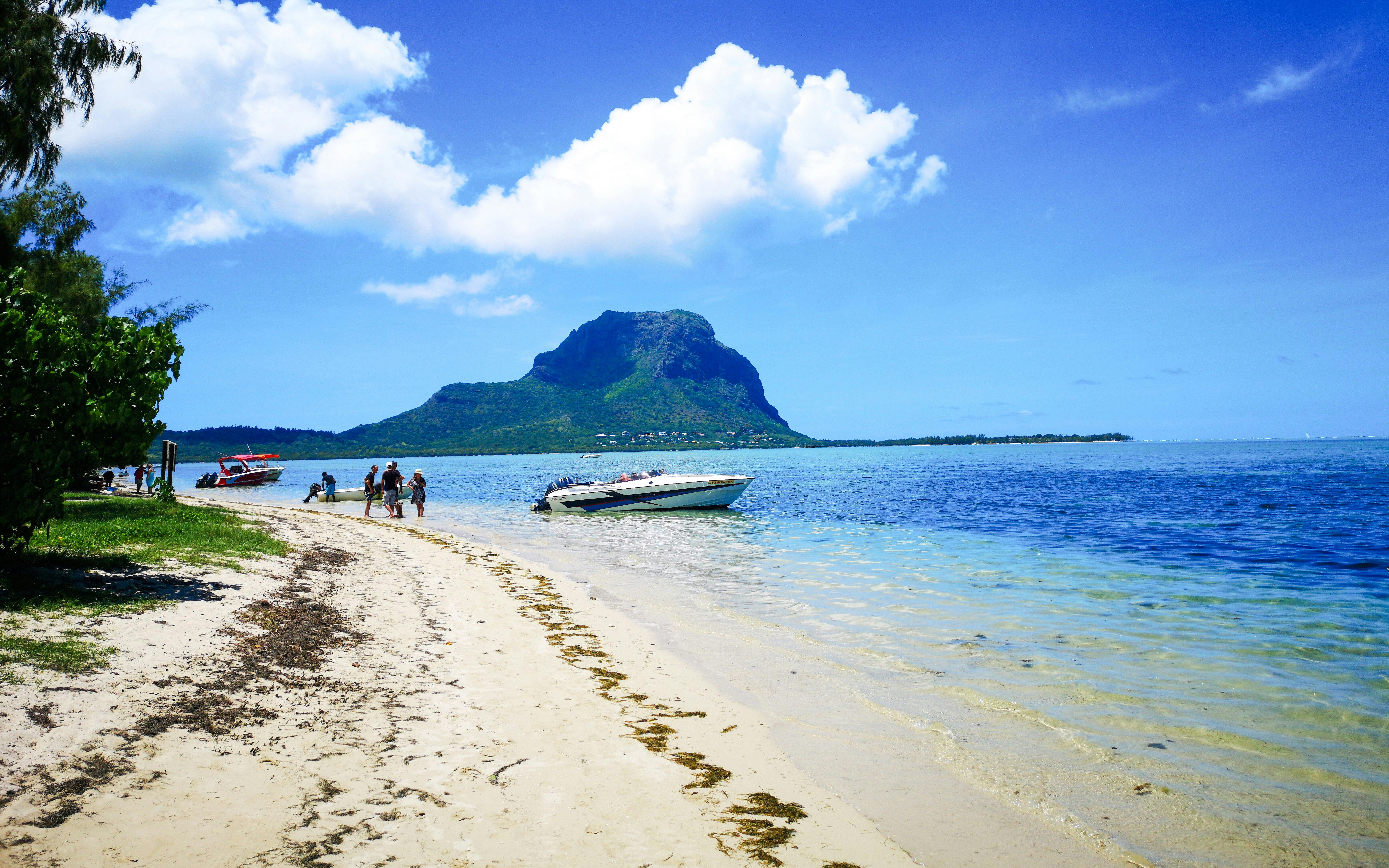 Boats anchored near Île aux Bénitiers beach, Mauritius, with Le Morne Brabant in the background.