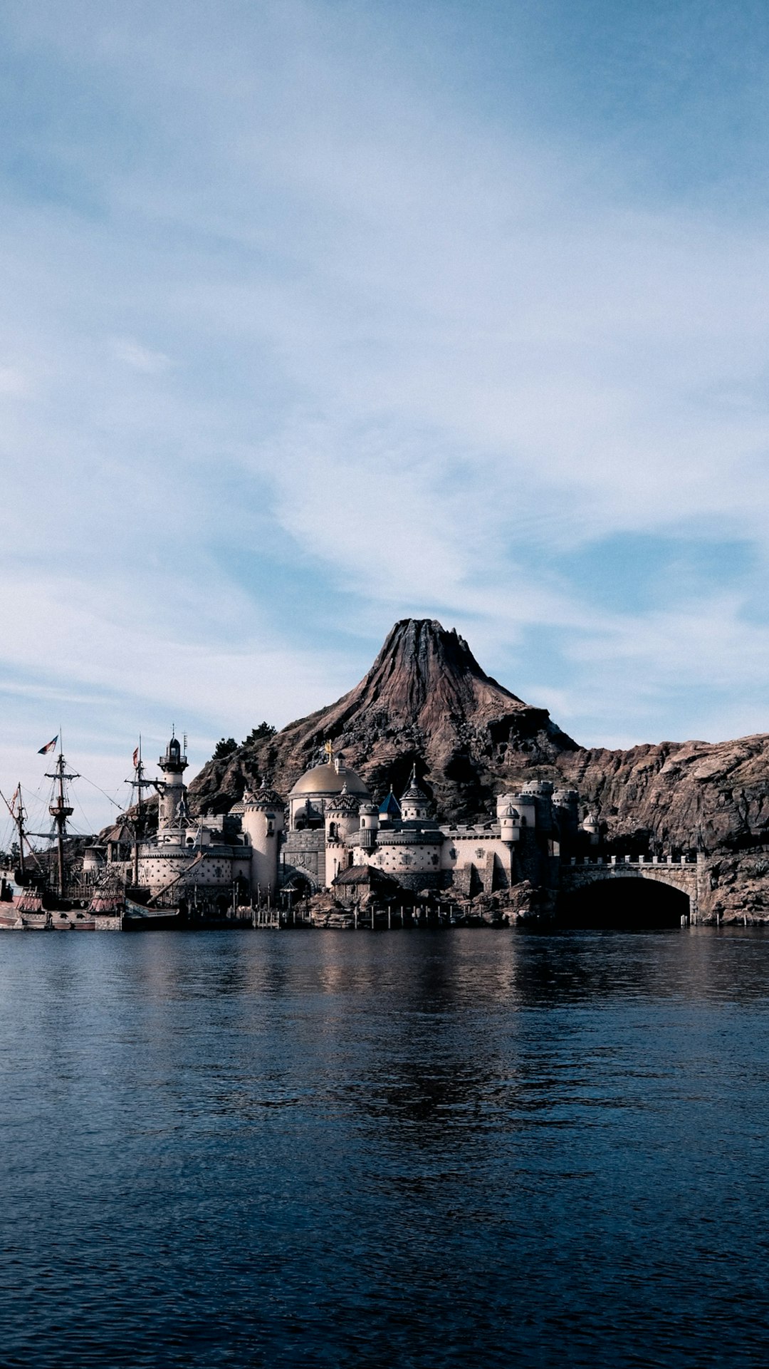 A fantasy castle overlooks a calm body of water