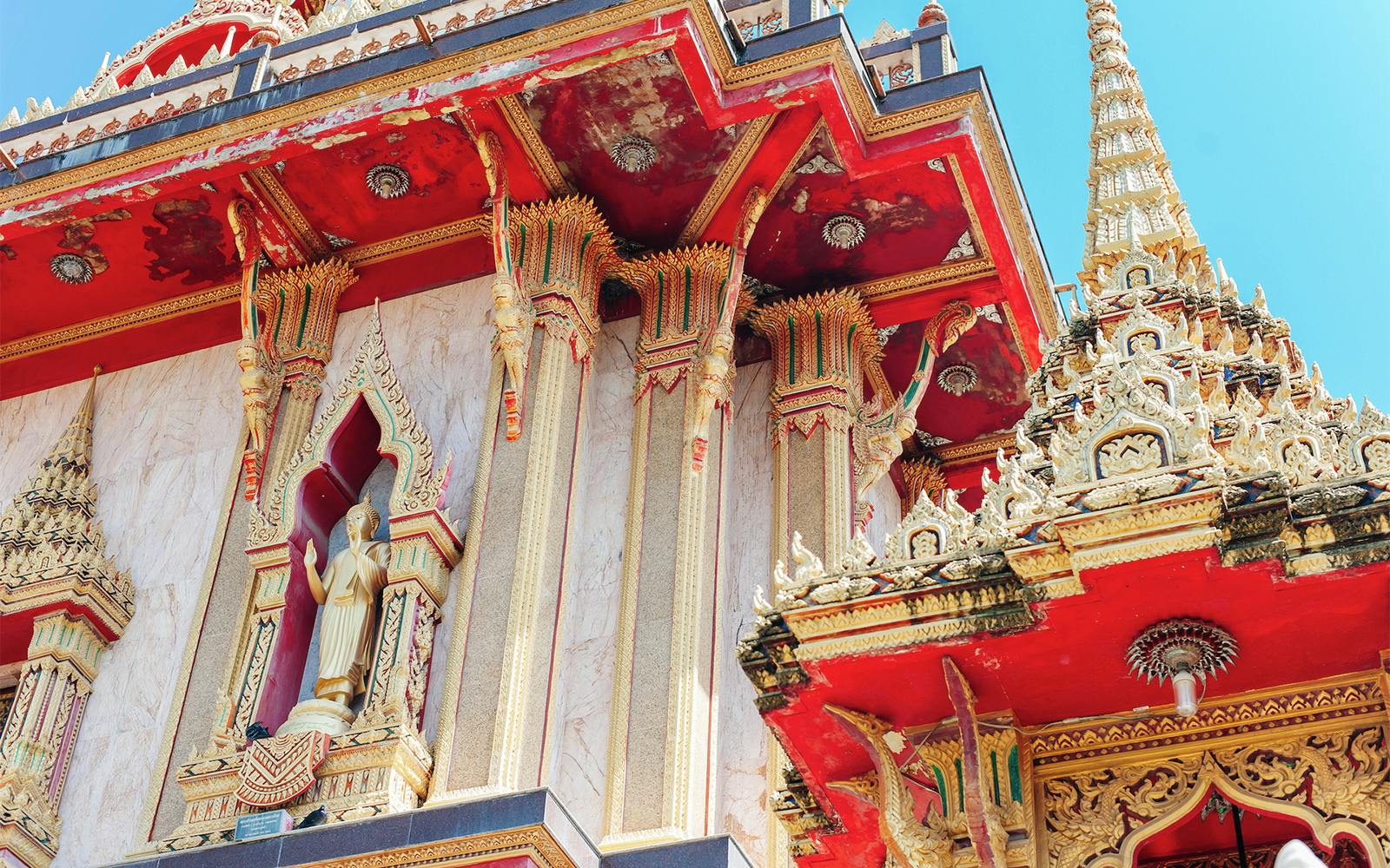 Wat Chalong temple architecture in Phuket, featuring ornate red and gold details.