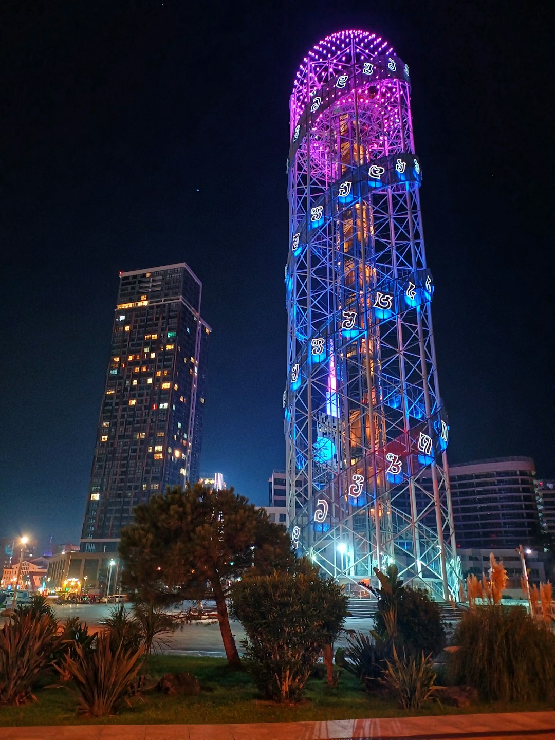 Tall, colorful illuminated tower and skyscraper at night