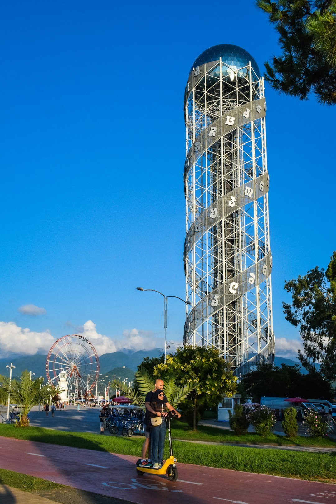 a man riding a scooter down a street next to a tall tower