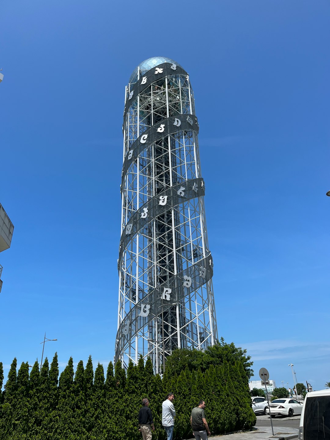 a tall metal tower sitting next to a lush green hedge