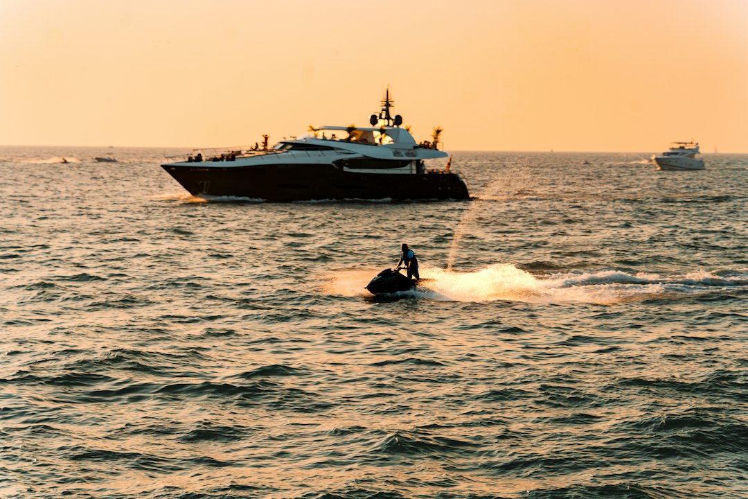 A yacht and jet ski on the water at sunset