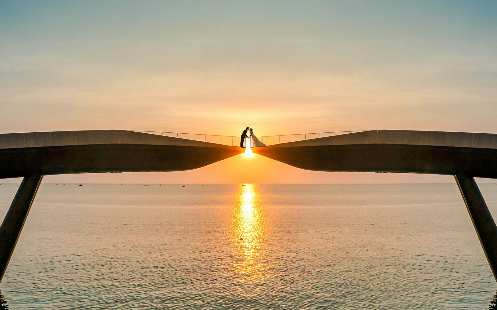 Couple on Kiss Bridge at sunset, Phu Quoc Island, Vietnam.