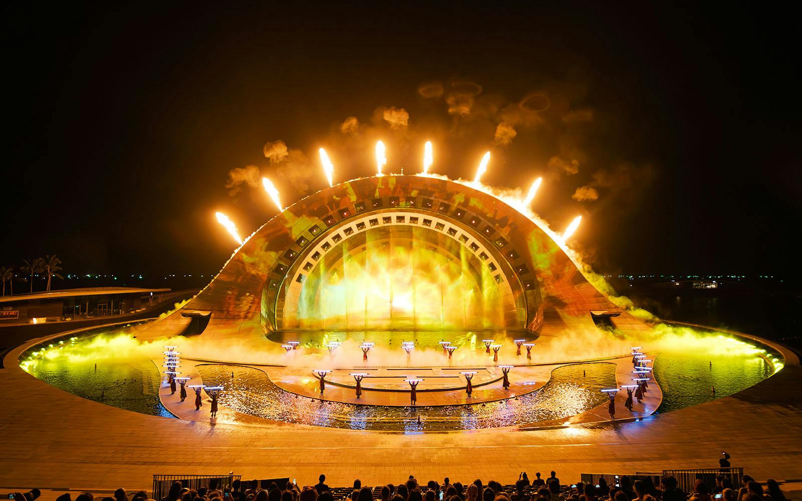 Performers with fire effects at Kiss of the Sea Show, vibrant stage lighting.