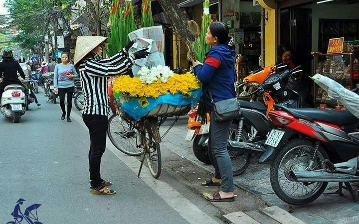 Hanoi street vendor selling flowers from a bicycle in the Old Quarter.