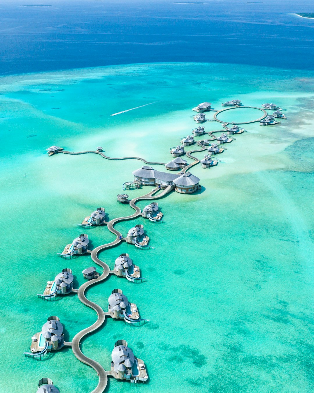 Aerial view of overwater bungalows connected by winding wooden walkways in Noonu Atoll, Maldives